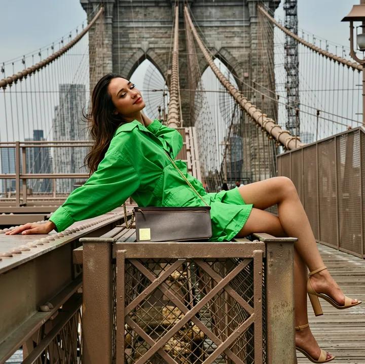 Woman in green on Brooklyn Bridge with recycled leather bag